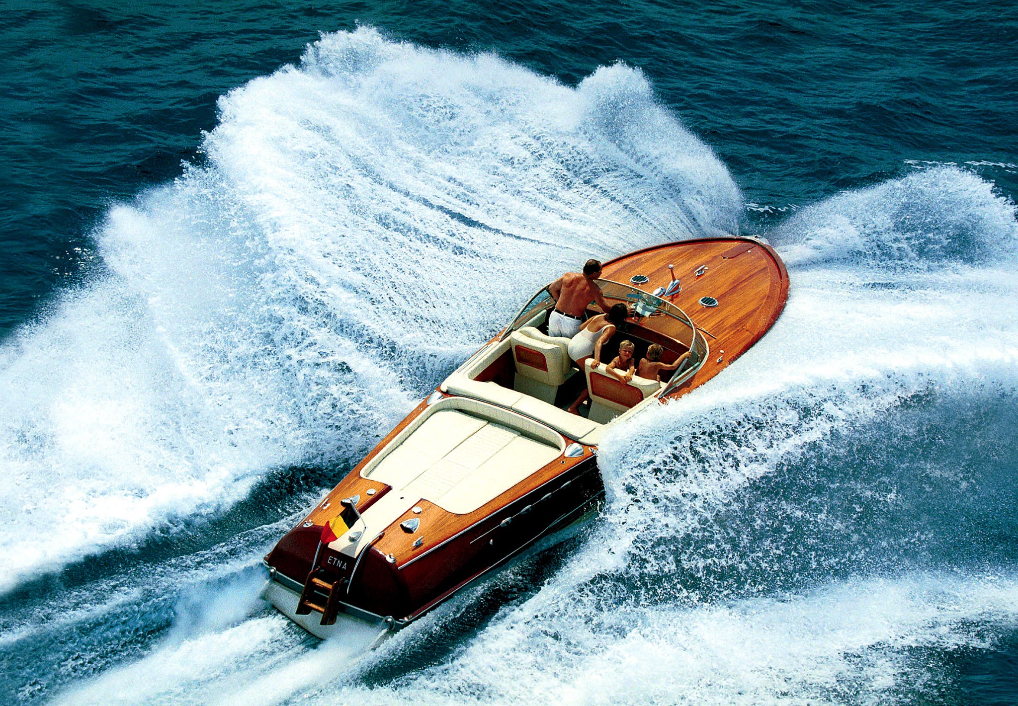 A wooden tender crossing the water from above